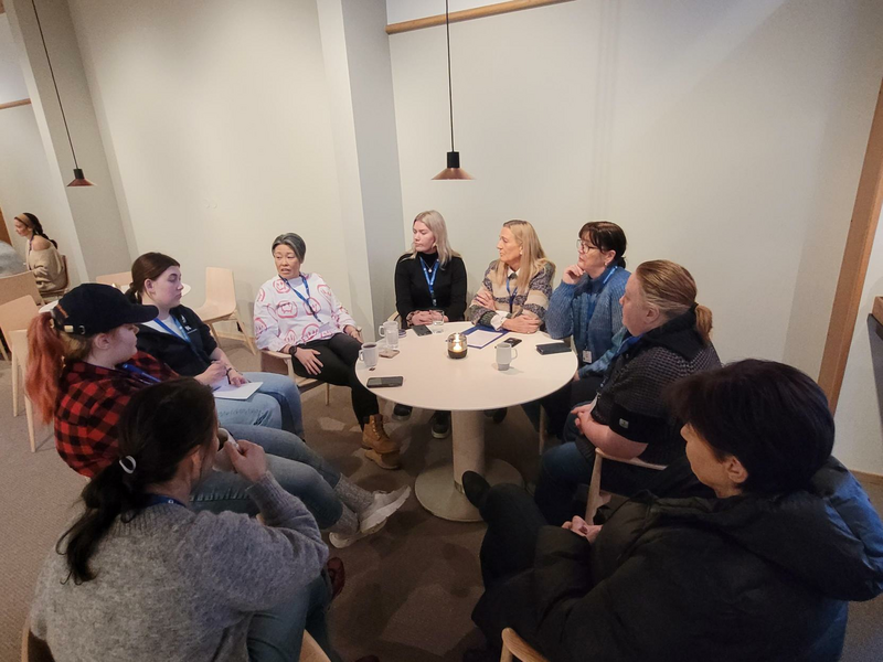 group of women sitting around a table discussing